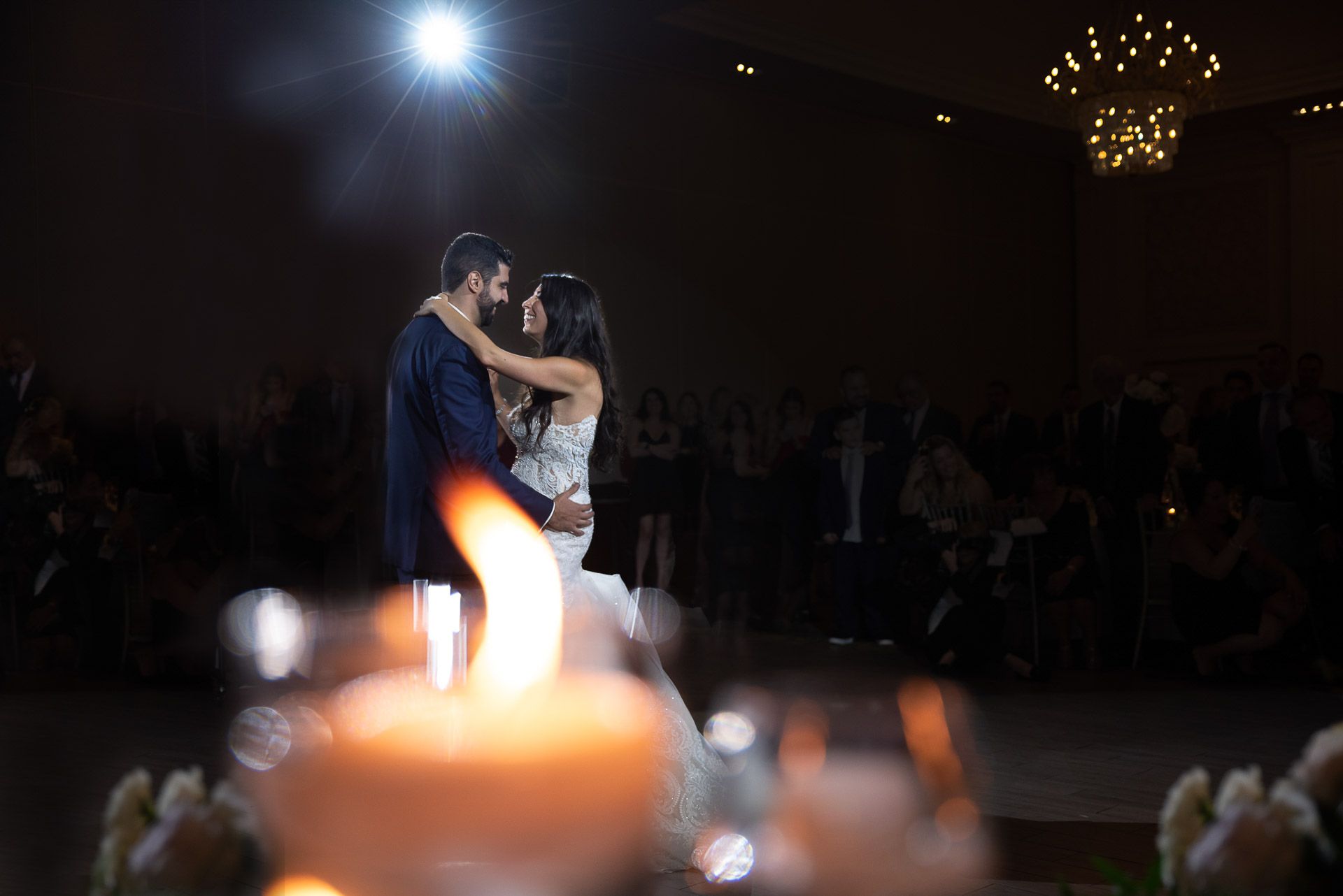 Couple shares romantic first dance spotlight at elegant wedding reception with candlelight.