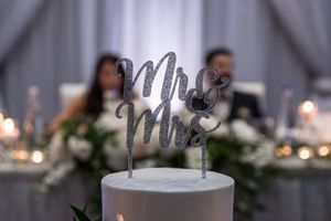 Silver glitter Mr & Mrs wedding cake topper on white cake at reception.