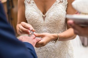 Bride places wedding ring on grooms hand during an elegant wedding ceremony.