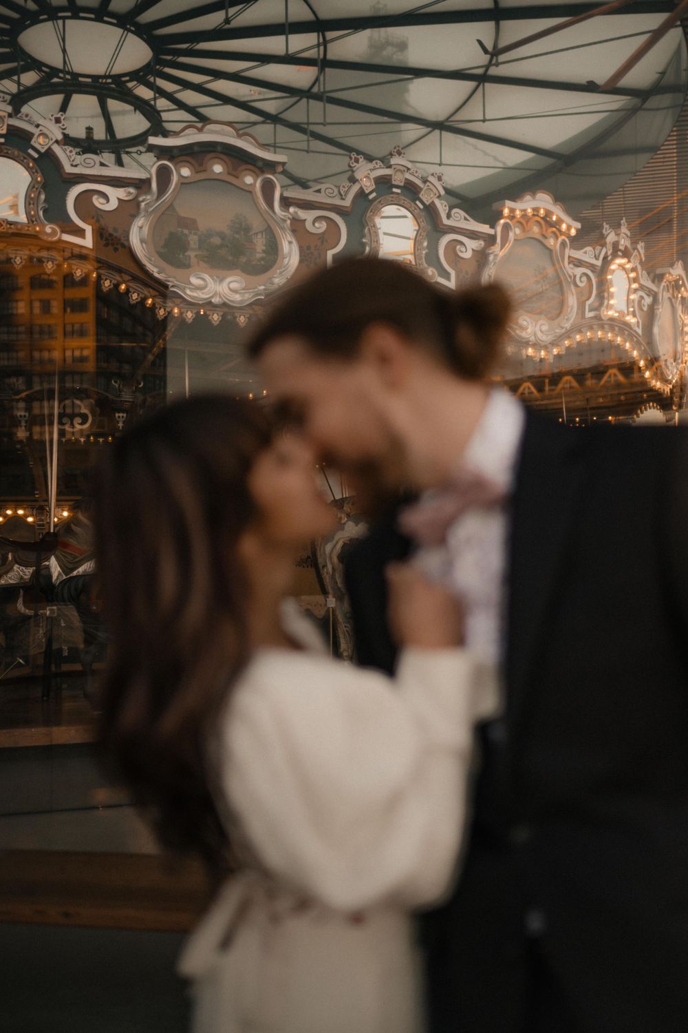 Dreamy wedding portrait with carousel lights creating a magical atmosphere.