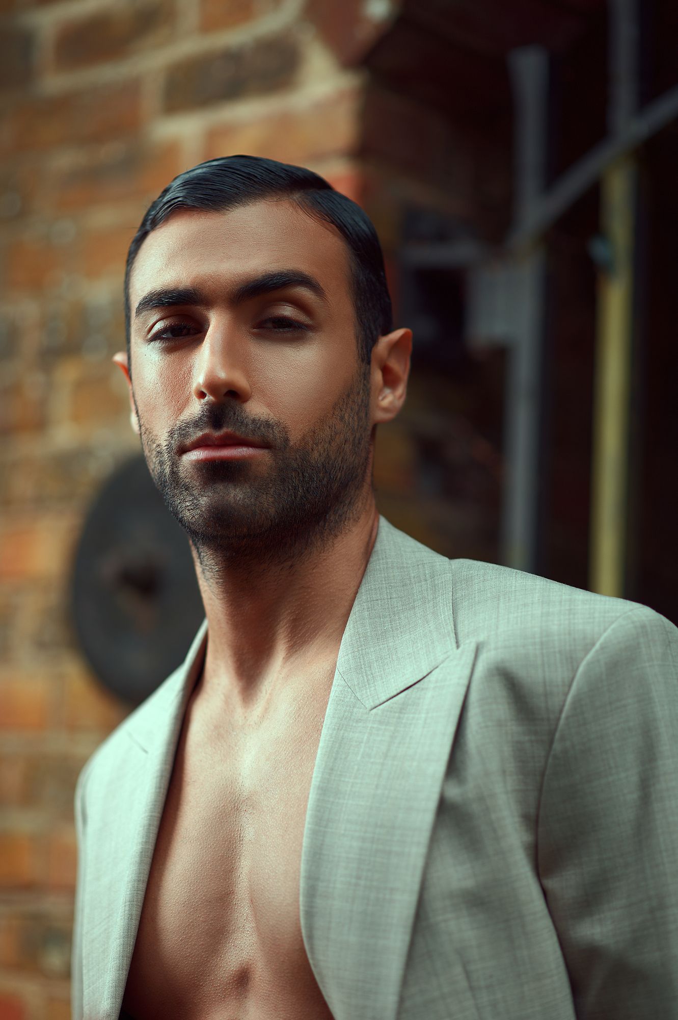 Fashion portrait against brick wall wearing light blazer.