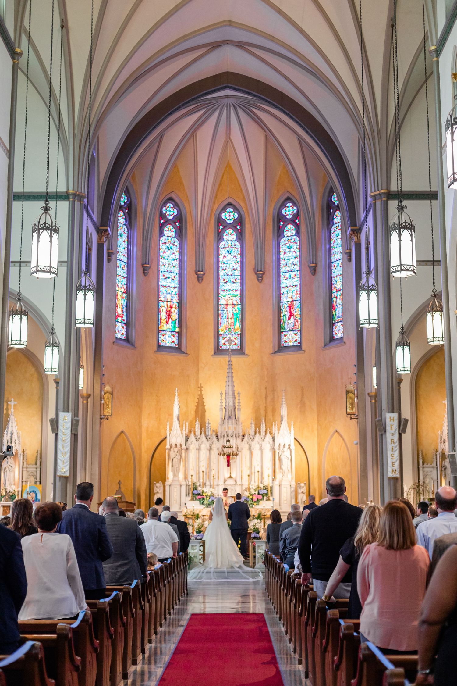 Cathedral interior with vaulted arches and stained glass windows during wedding ceremony.