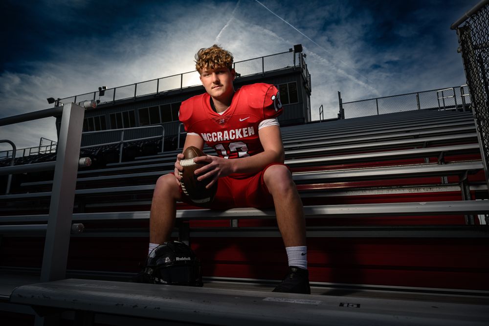 Football player in red uniform sits on stadium bleachers at dramatic angle.