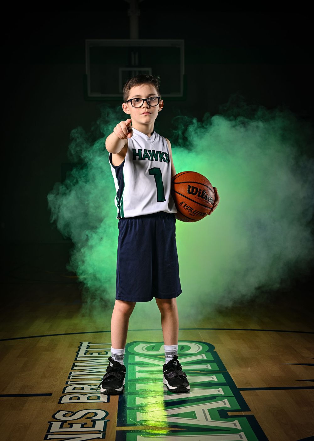 Basketball player poses dramatically with green smoke effects on illuminated court.