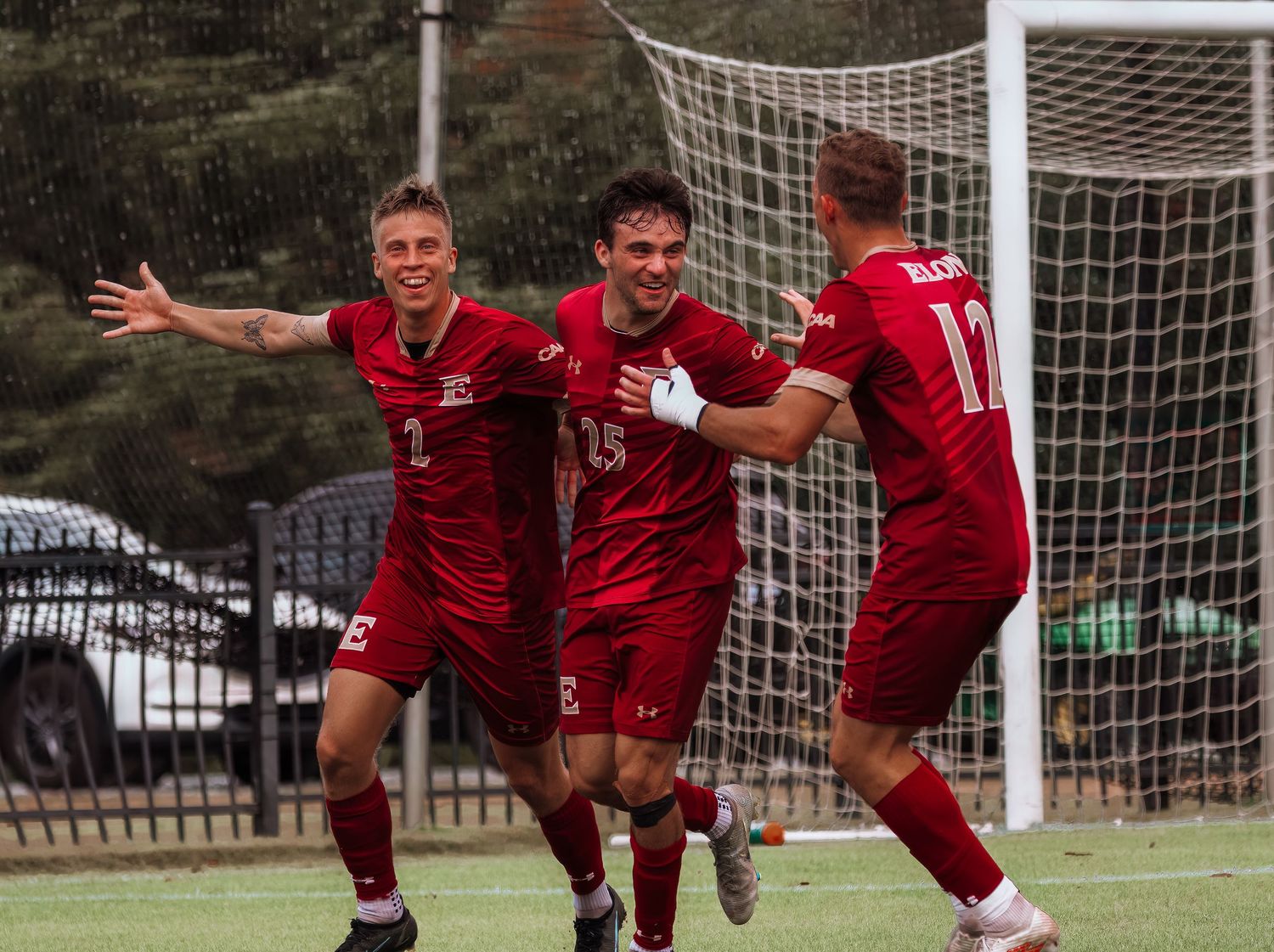Soccer players celebrate scoring goal in front of net during match.