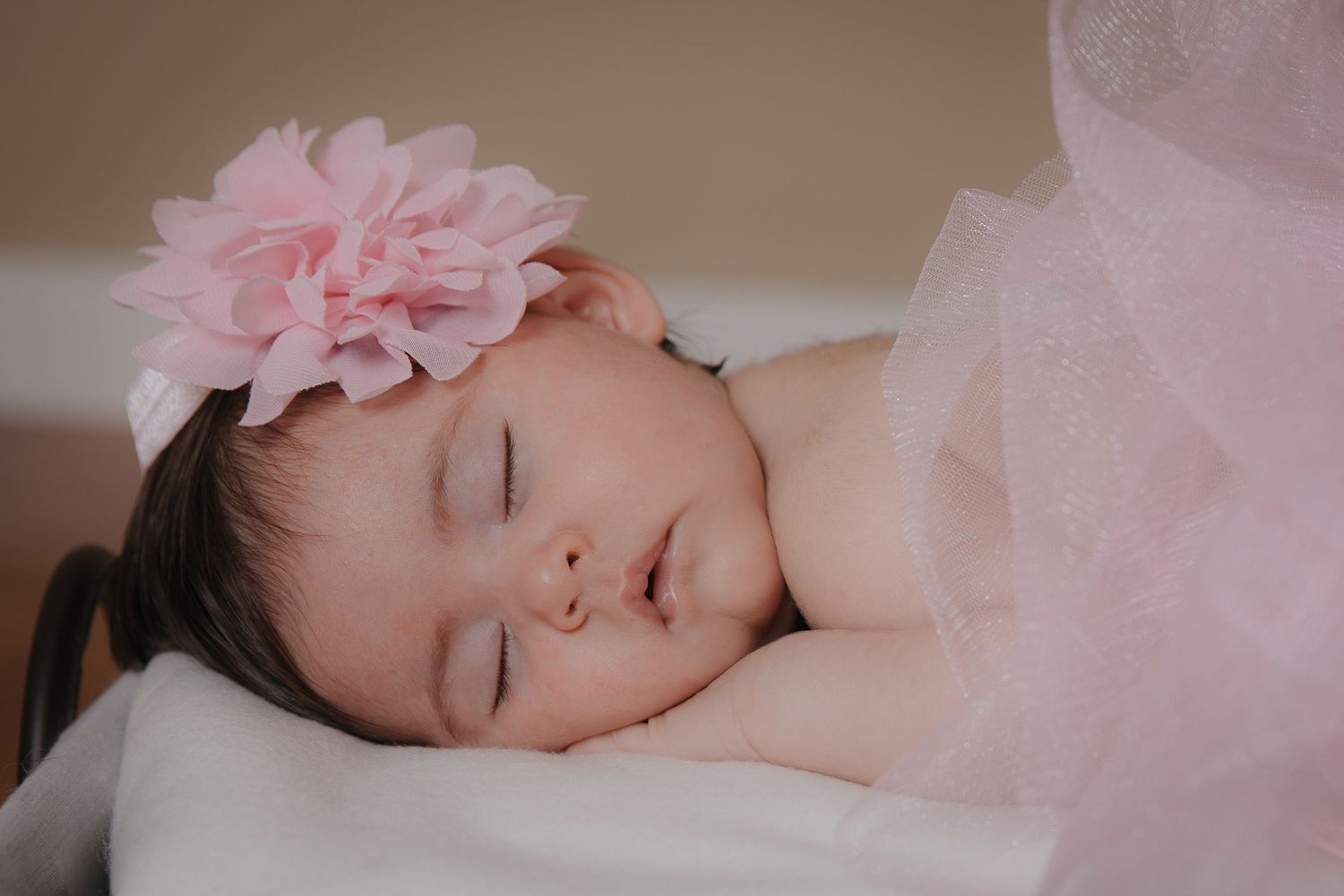 newborn baby girl with a pink flower in her hair