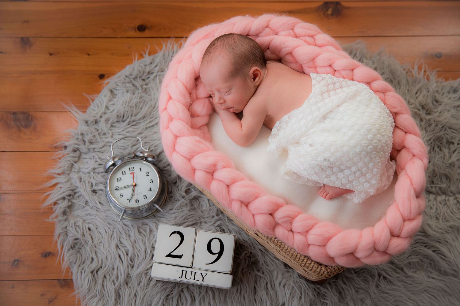 newborn baby girl in a basket with date and time announcement