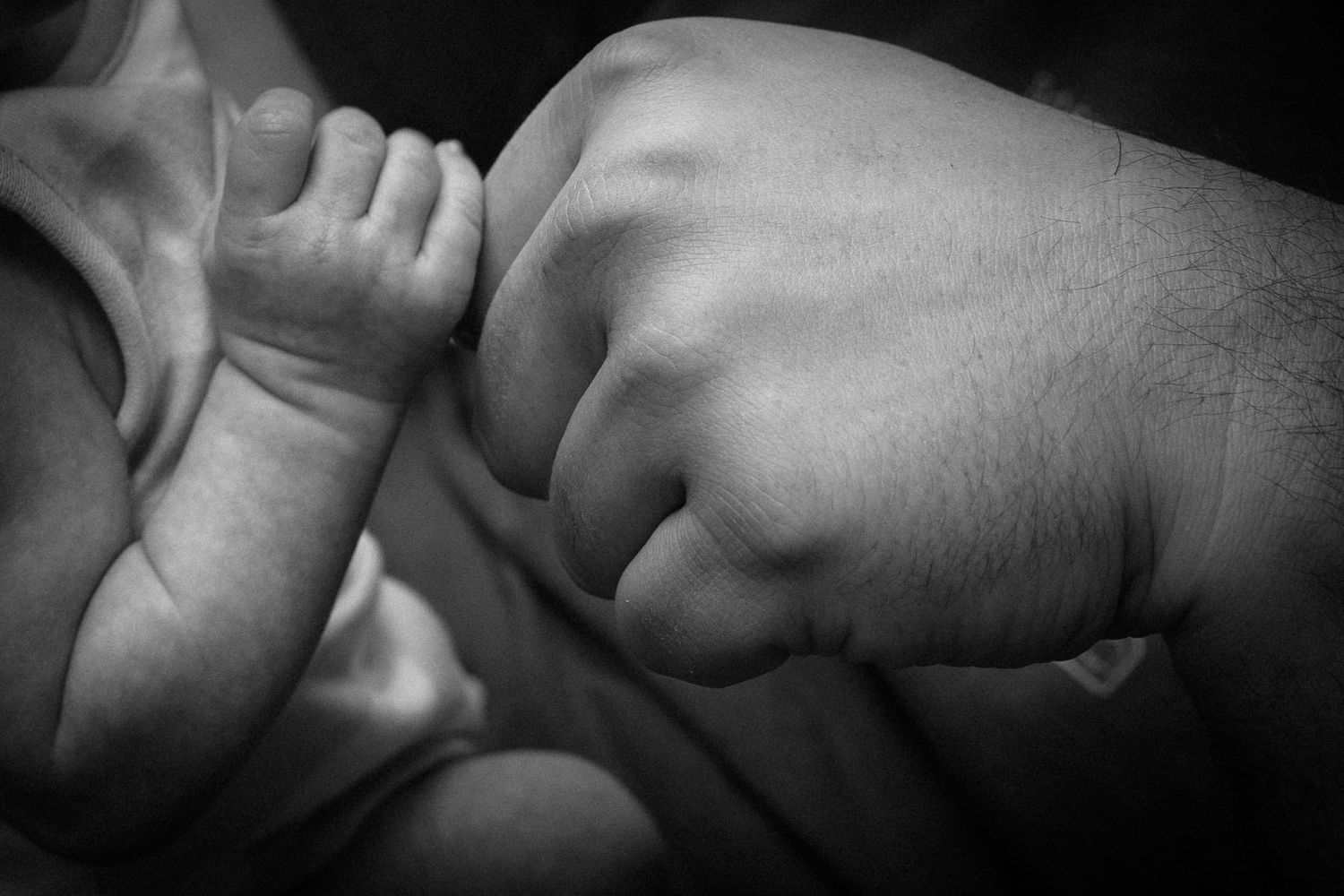 newborn baby fist compared to dads in black and white