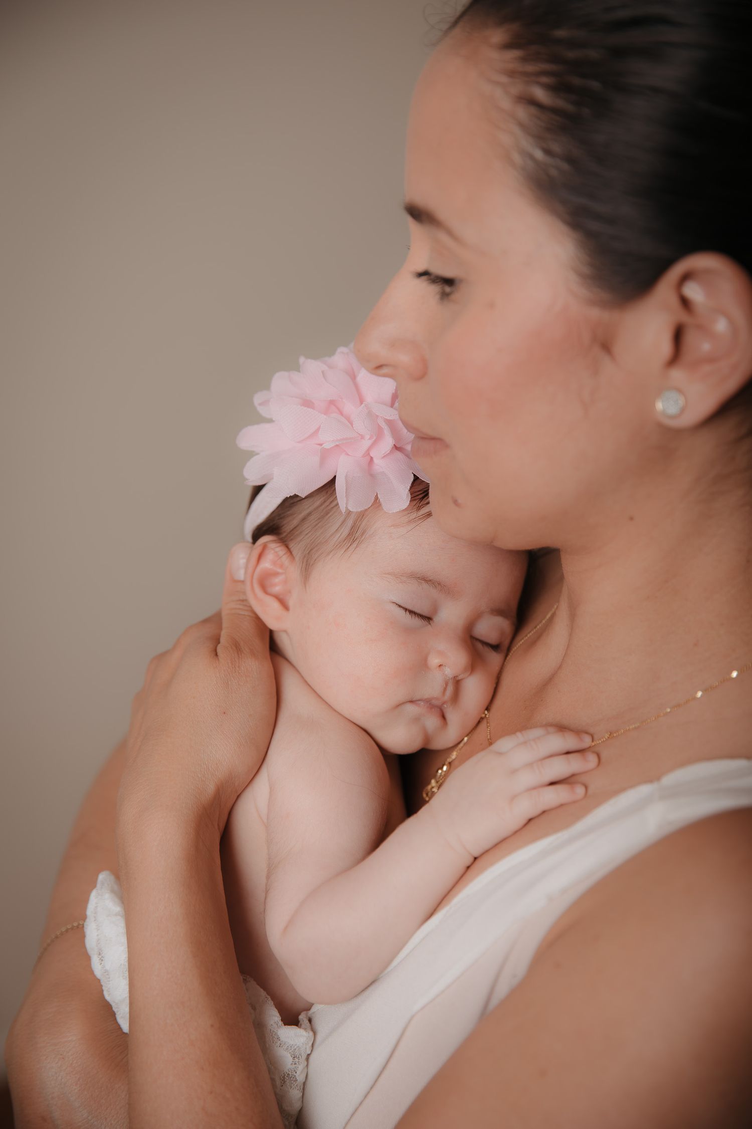 mum holding newborn baby girl with pink ribbon