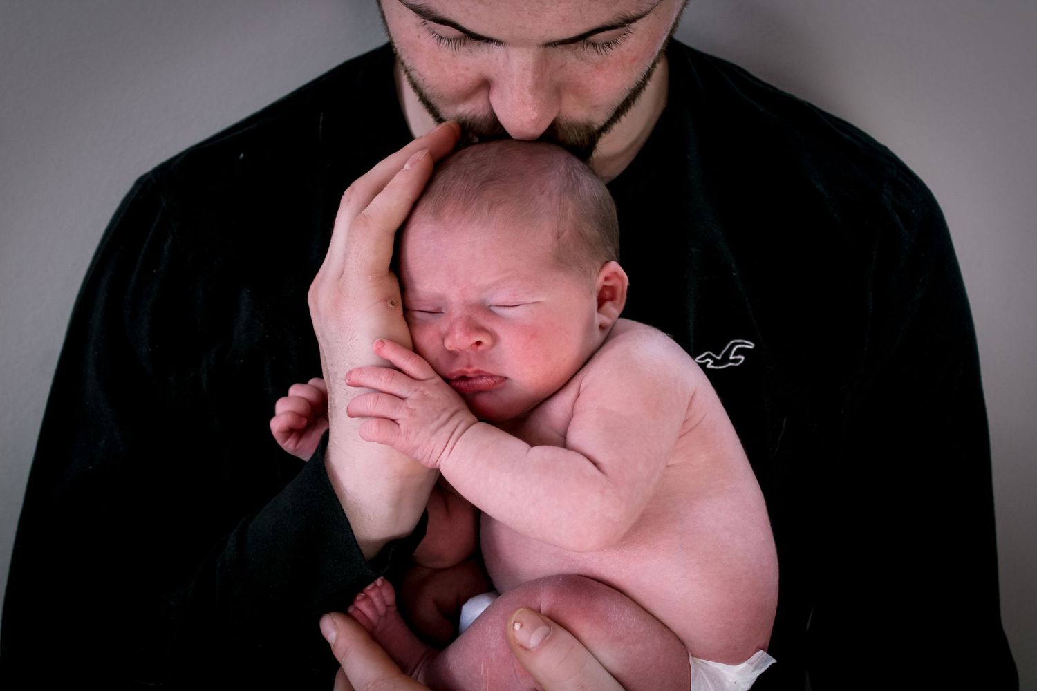 Series of black and white photos showing a newborn being positioned during a photography session.