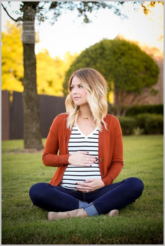 Maternity style featuring striped shirt and rust cardigan in outdoor autumn setting.