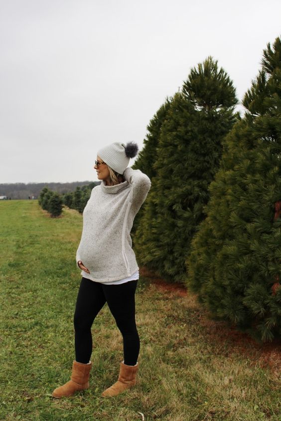 Winter maternity look with beanie hat, cozy sweater and boots at Christmas tree farm.