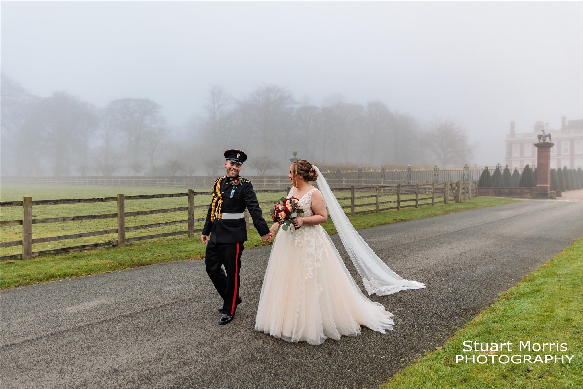 Bride and groom walk through the grounds of Knowsley hall on a foggy day. Liverpool wedding photographer