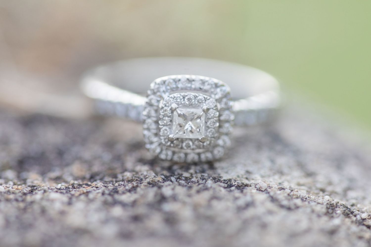 Close-up of a sparkling diamond engagement ring set against a textured stone surface.