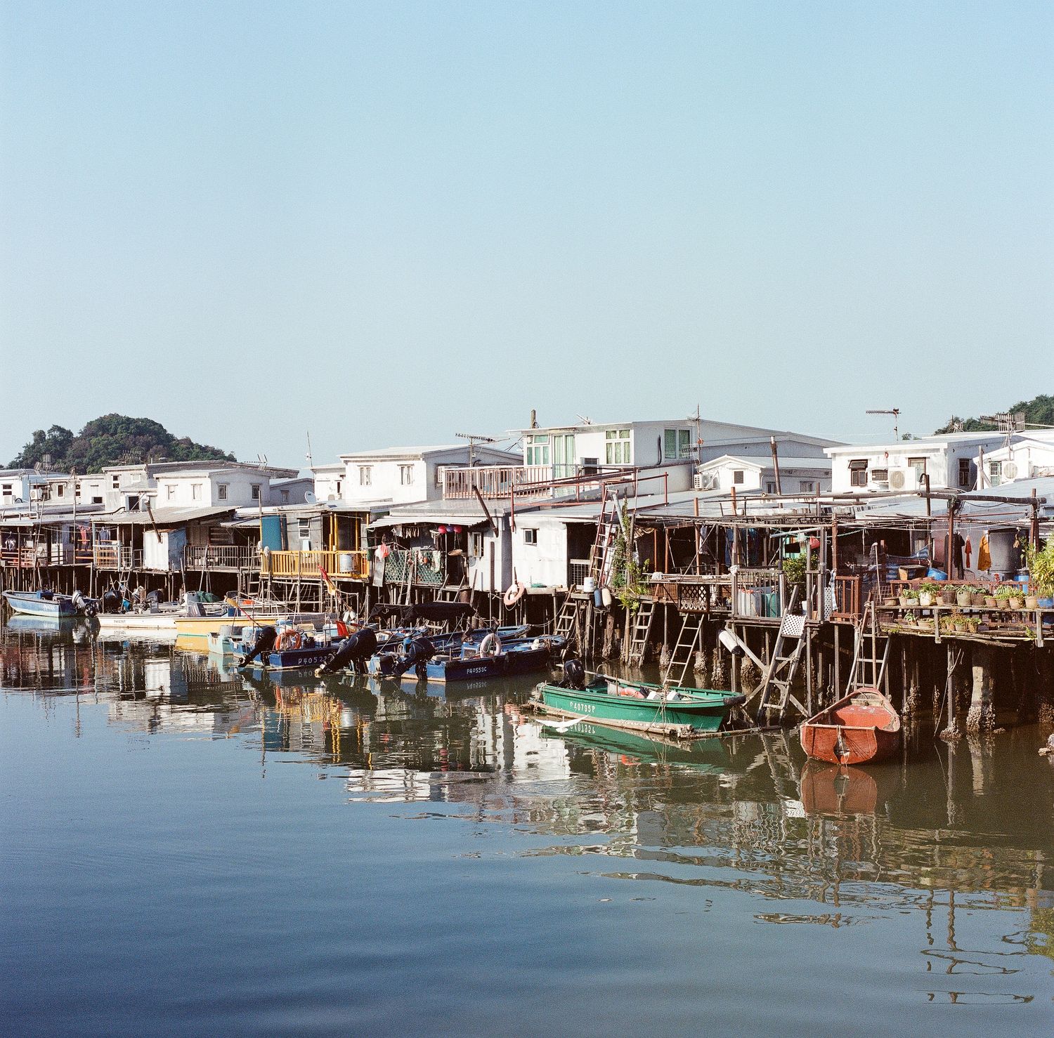 Floating houses above water with small boats attached to its railing in Tai O, Street & Travel Photography.