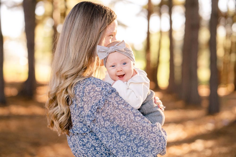 Loving embrace between parent and baby photographed in a sun-drenched autumn forest.