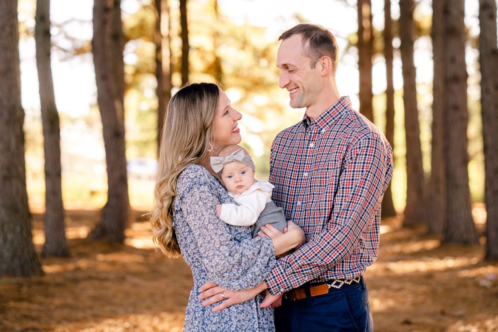 Intimate family moment captured in a wooded setting with warm sunlight filtering through trees.