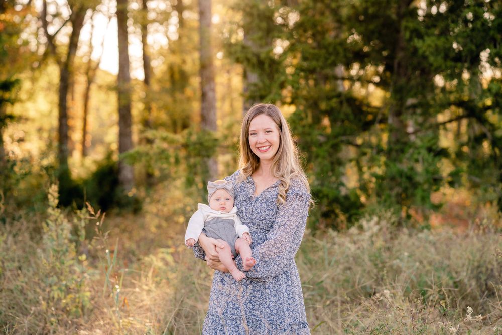 A peaceful family moment captured in a sunlit forest clearing with golden light filtering through trees.
