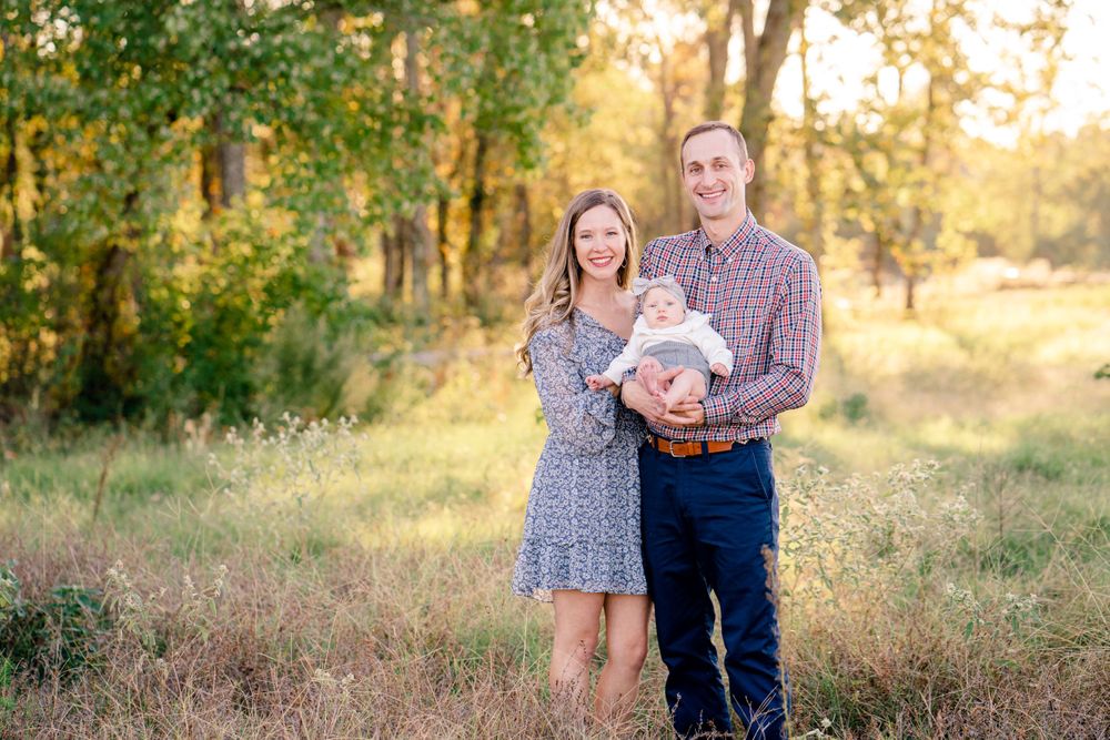 Family portrait outdoors at sunset in natural field setting.