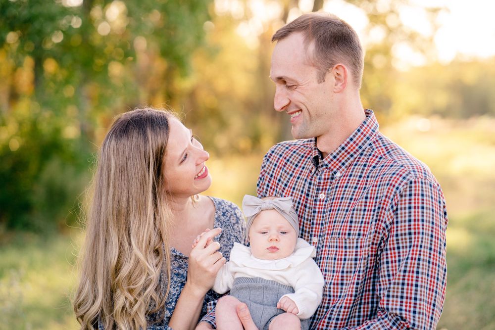 Outdoor family portrait with baby in grey outfit during golden hour.