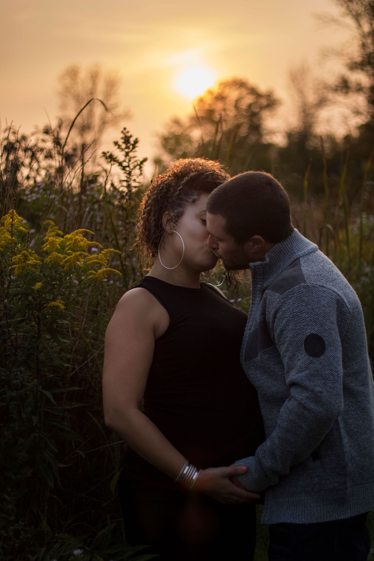 Romantic sunset photoshoot in a field with tall grass and golden lighting.