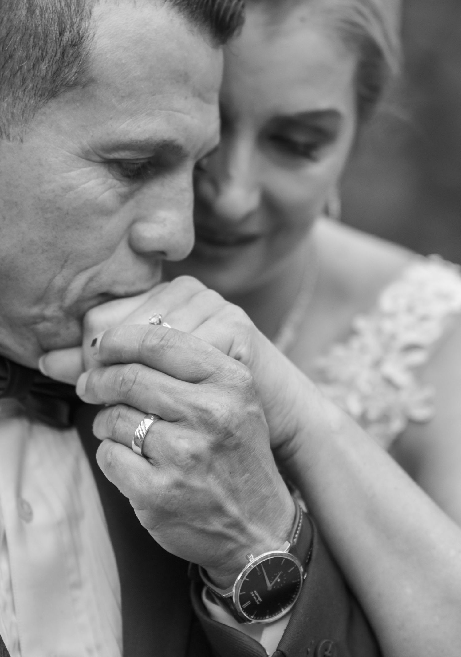 Intimate black and white moment of couple displaying their wedding rings.