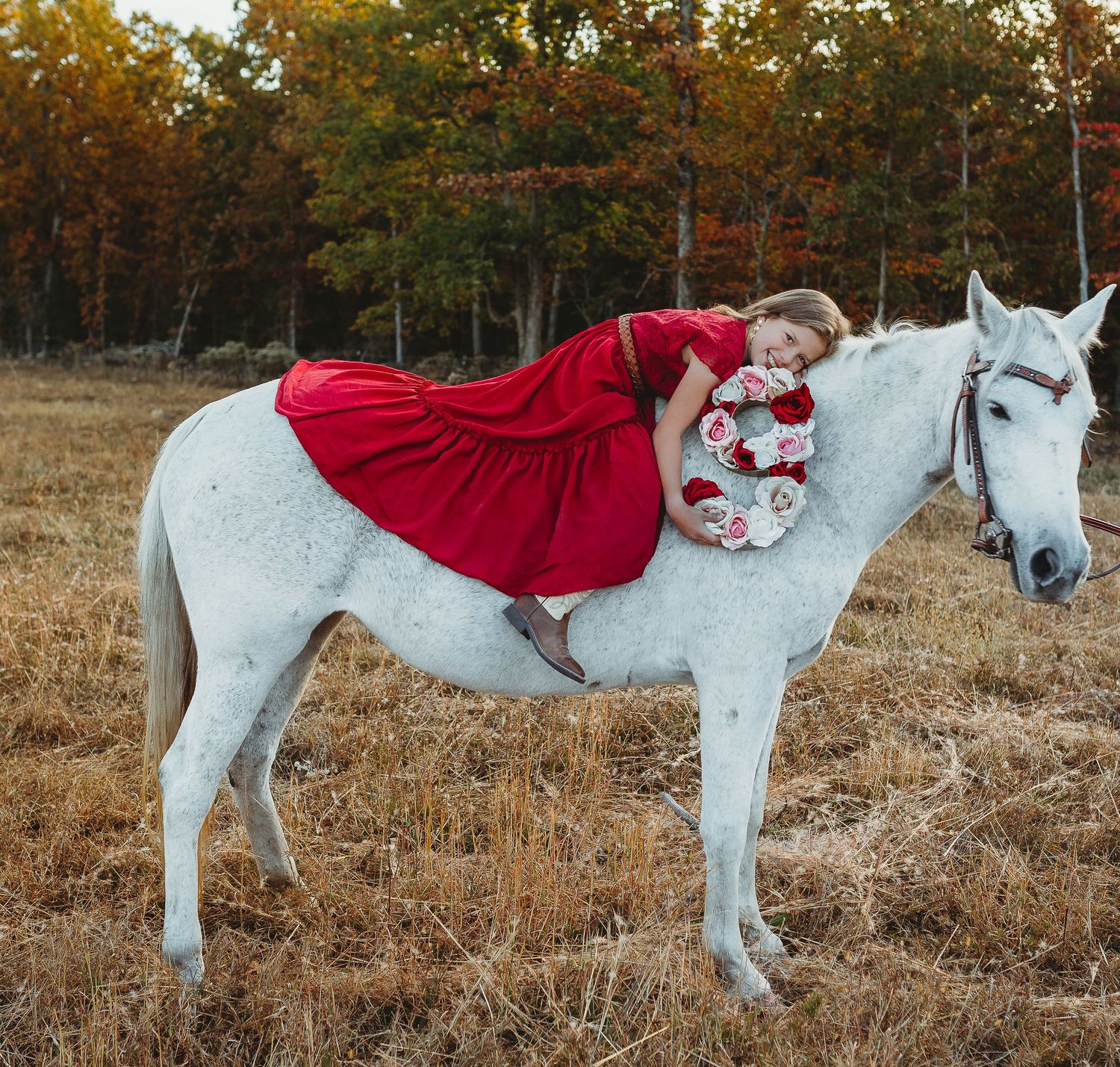 young girl in vibrant red dress on white horse hold a flower 9 for her birthday photoshoot