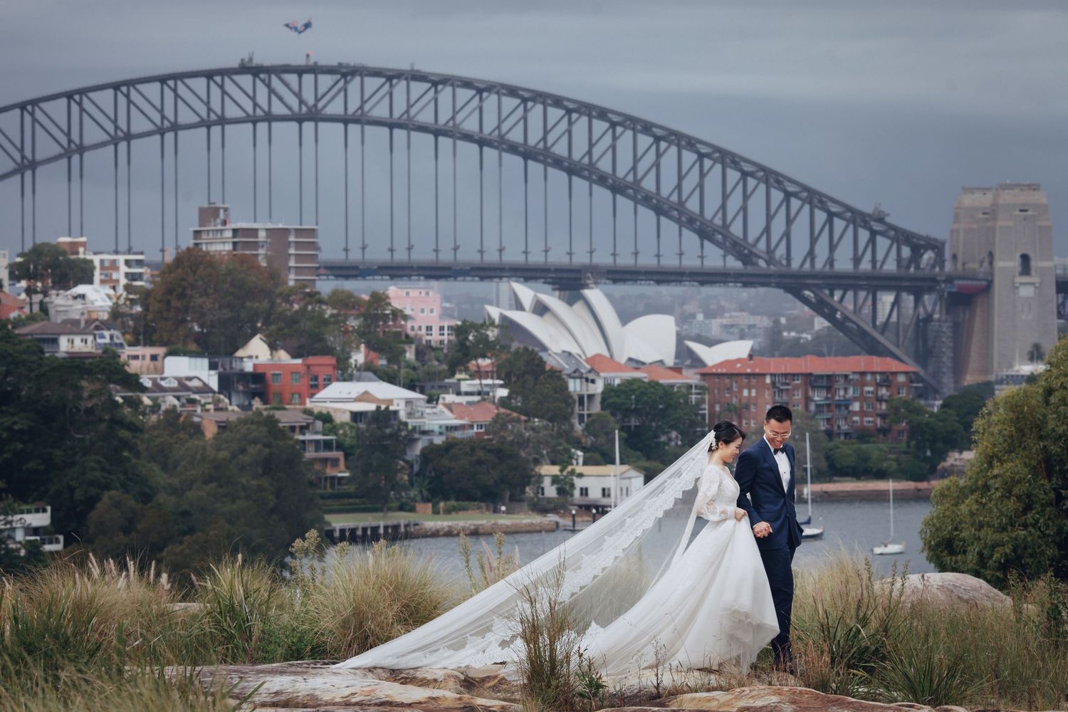 Bride and groom posing with Sydney Harbour Bridge and Opera House in background.
