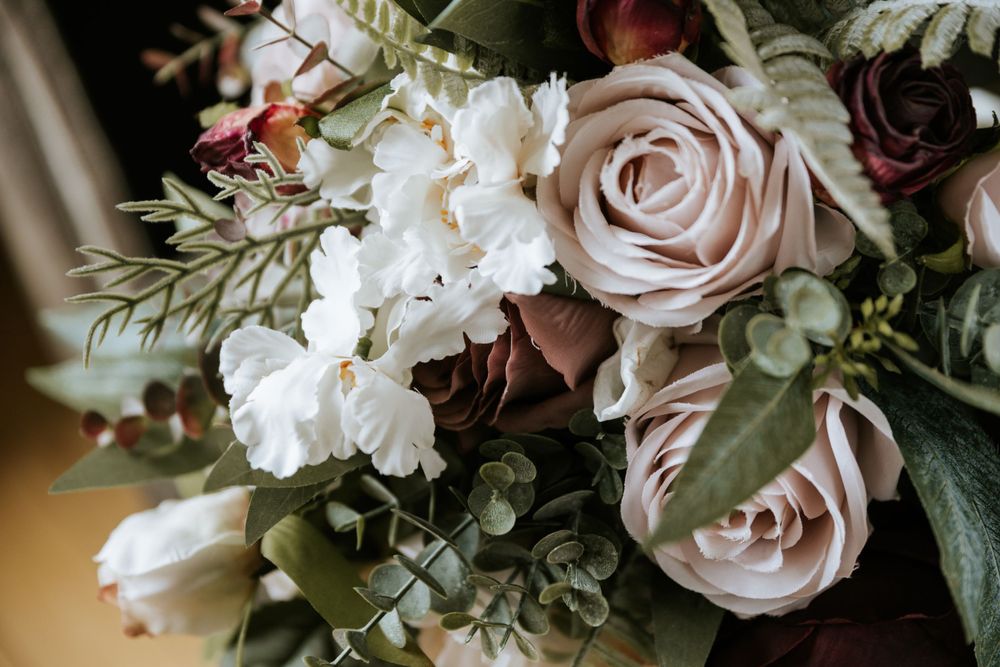 Wedding bouquet with white and blush roses and mixed greenery.