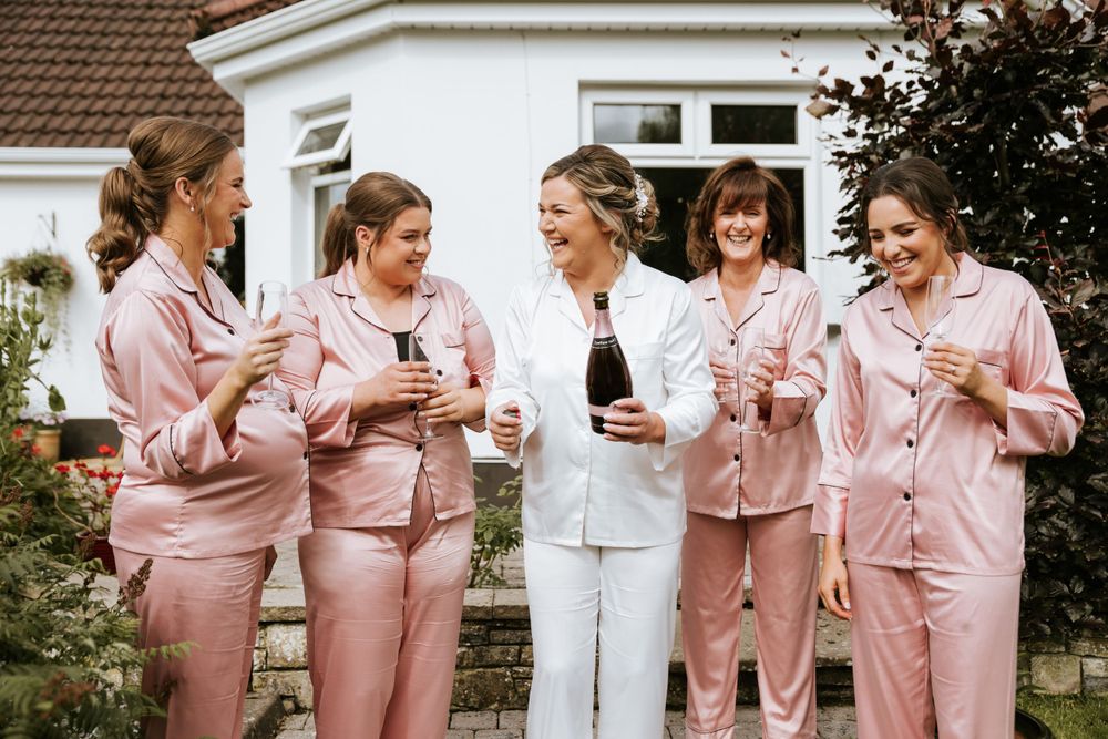 Group wearing matching pink robes during wedding preparations.