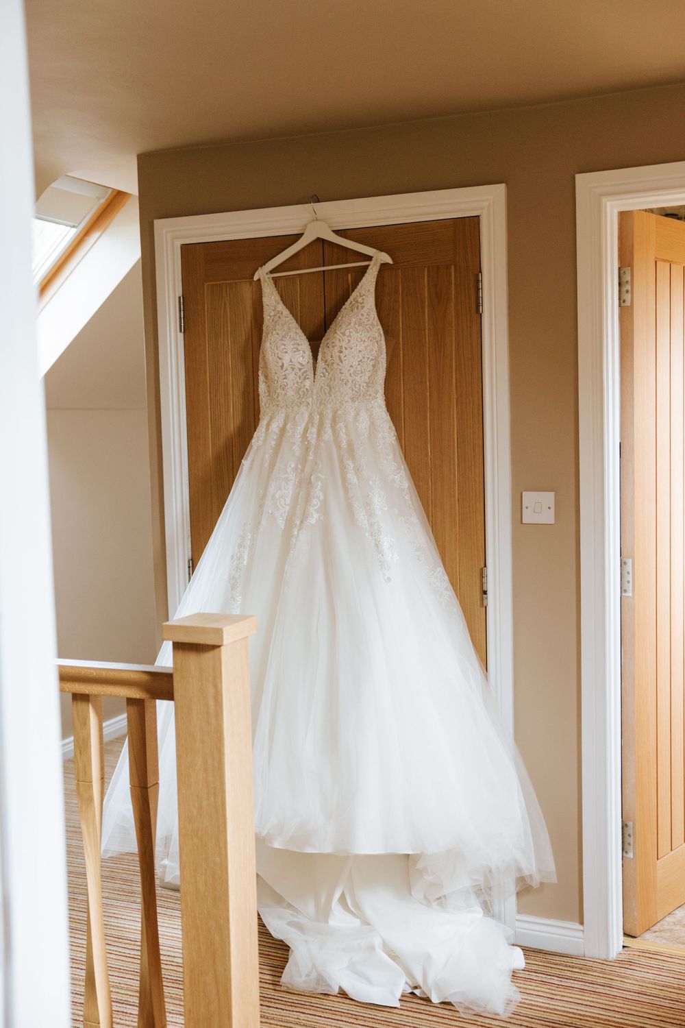 Collection of white wedding dresses hanging in a sunlit room.