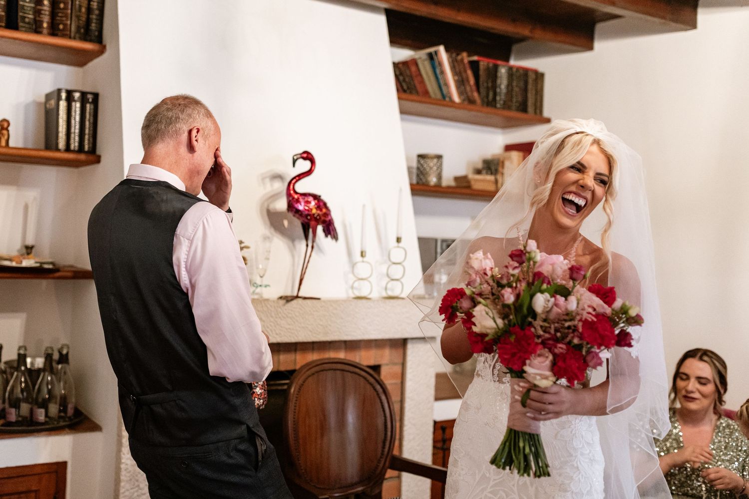 A candid moment of laughter during a wedding celebration with a beautiful bouquet of red and pink flowers at Quinta da Bichinha