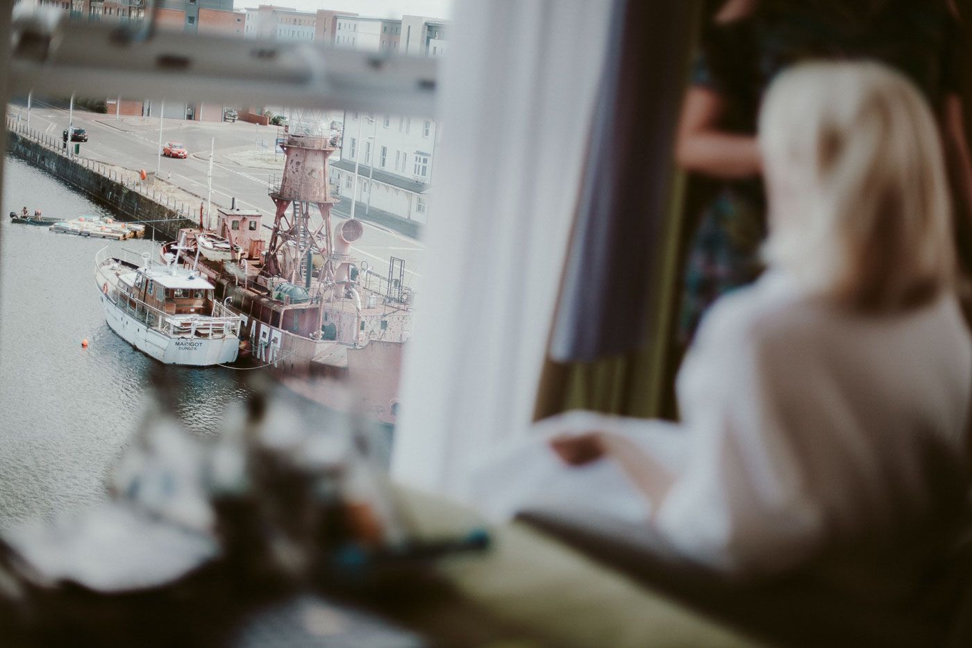 View of boats in harbor through window with silhouette in foreground.