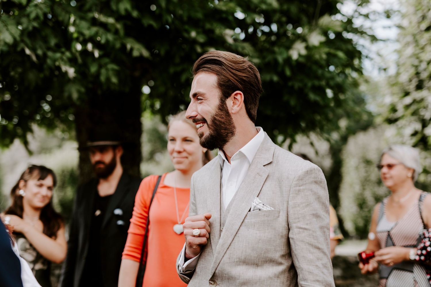 Wedding guests enjoy drinks and conversation in a garden setting.