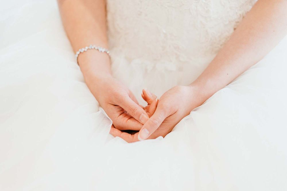 Close-up of bride's hands clasped together while wearing a delicate bracelet.