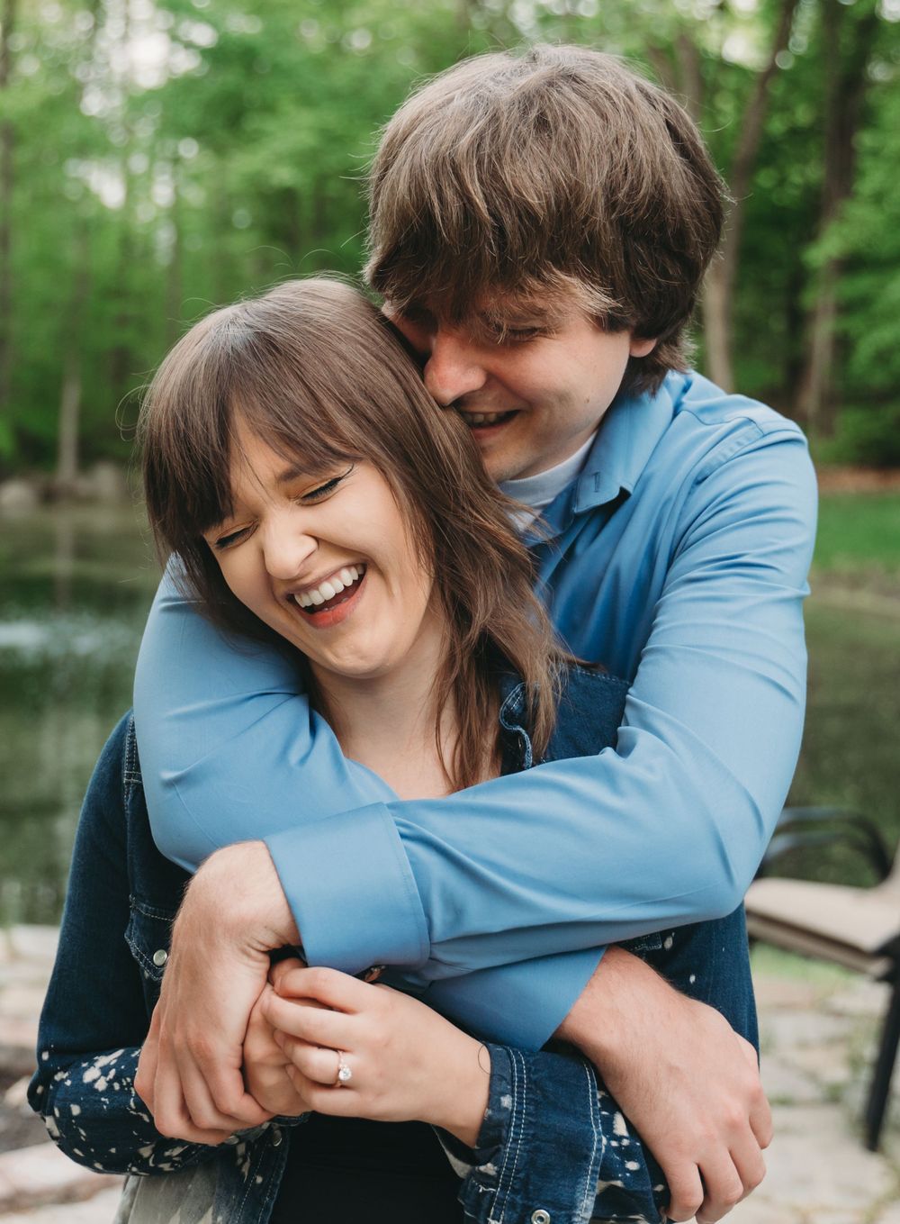 A joyful romantic moment captured outdoors with natural greenery in the background.