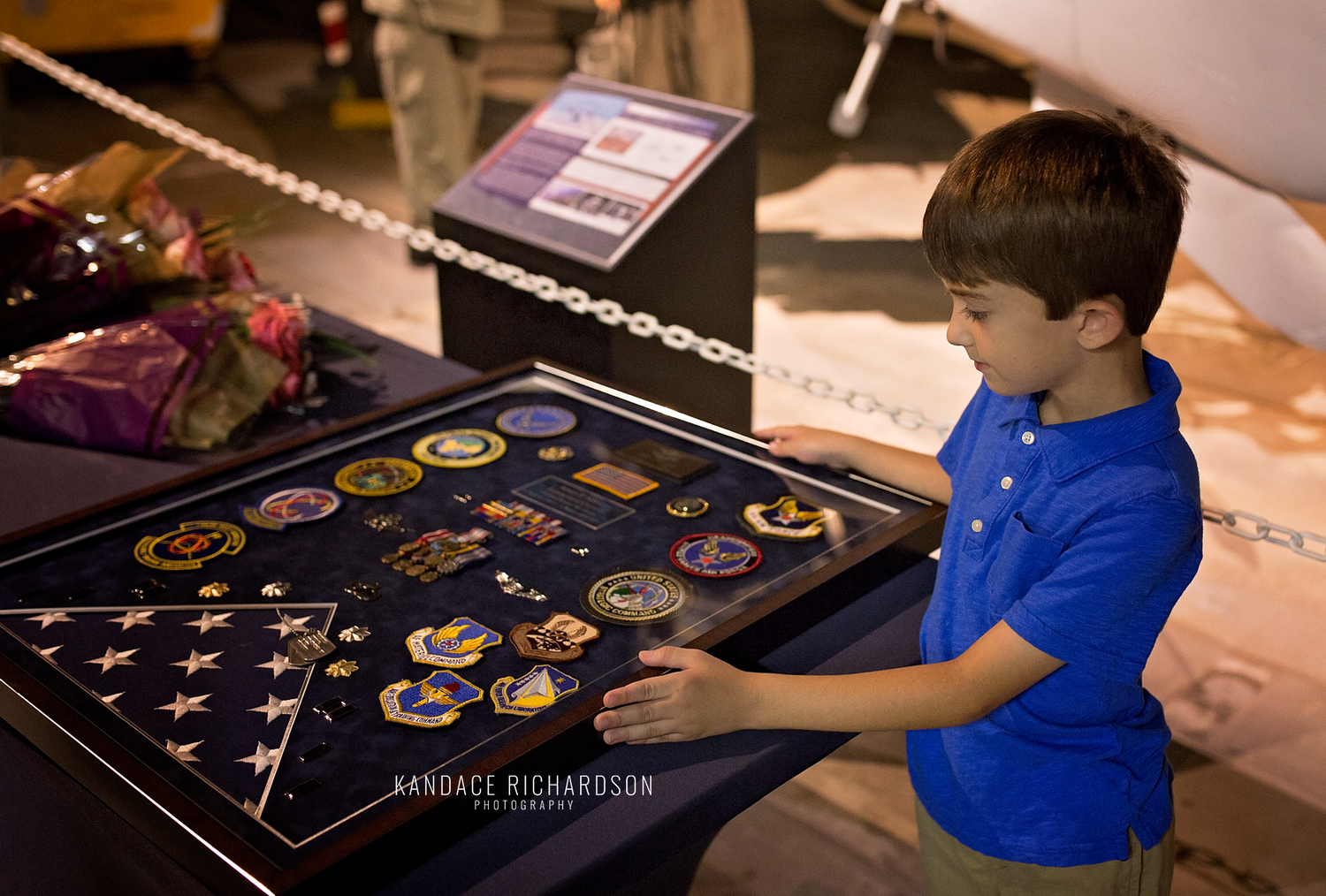 Young visitor examining military medals and patches in a display case at a museum.