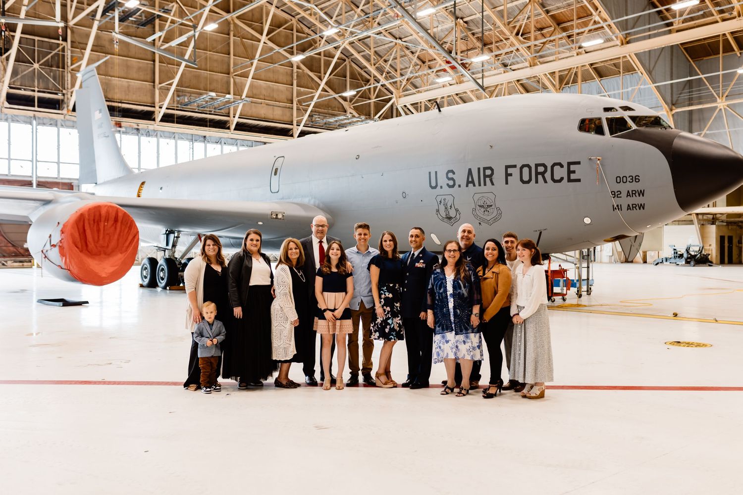 Group photo in front of US Air Force aircraft in hangar setting.