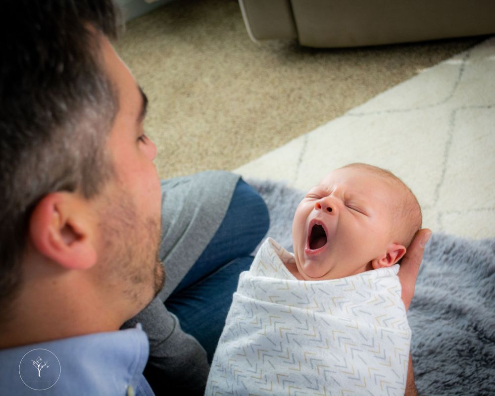 Close-up series captures tender family interactions with newborn on soft grey bedding.