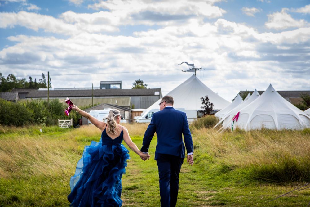 Bride with Louboutin Shoes and groom walking away glamping in Chittering Barns