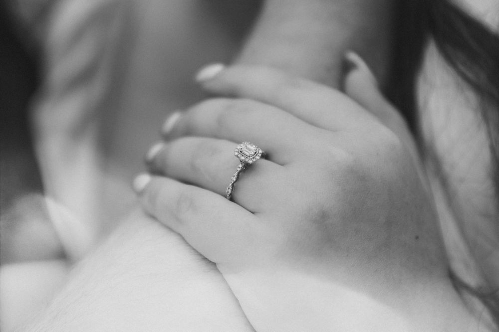 Black and white closeup of an engagement ring, highlighting its intricate design and symbolism of commitment and love.