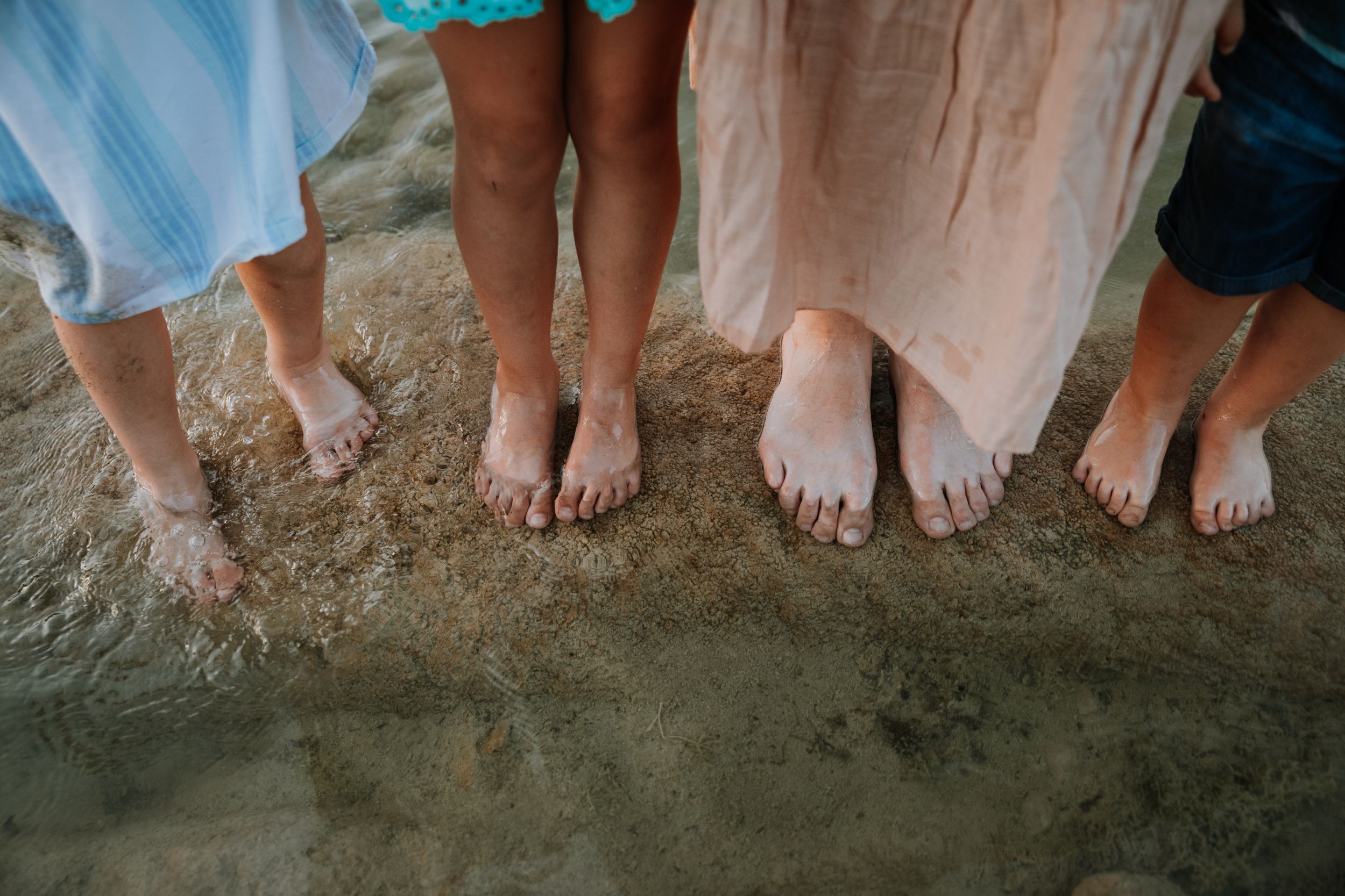 Feet of every family member standing together in the creek bed of Wimberley, TX, symbolizing unity and connection in nature.