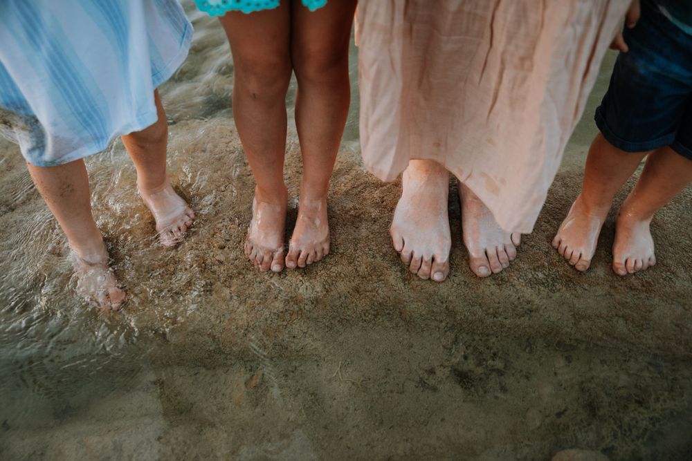 Feet of every family member standing together in the creek bed of Wimberley, TX, symbolizing unity and connection in nature.