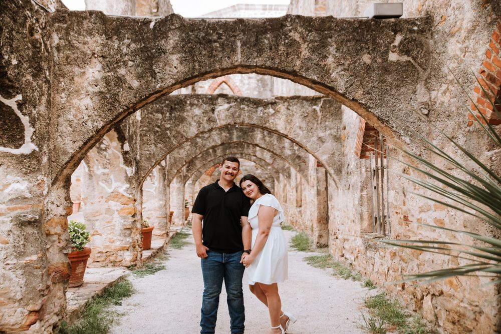 Engaged couple standing together at Mission San Jose in San Antonio, TX, capturing a romantic moment in front of the historic architecture.