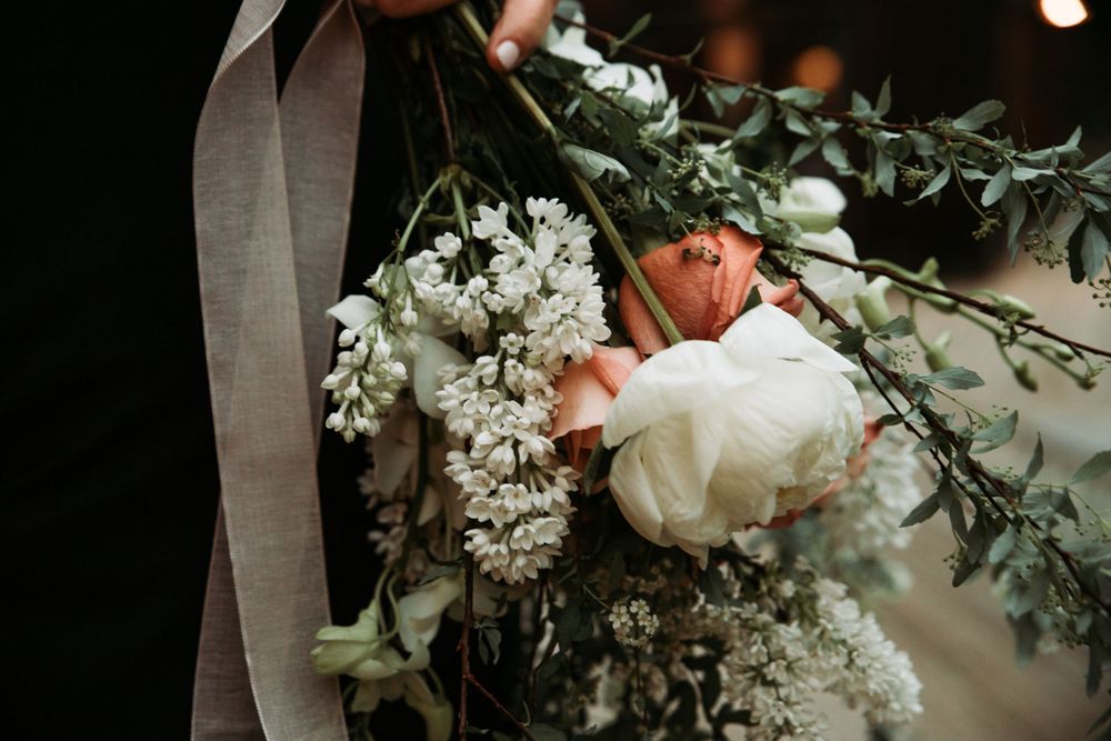 Bridal bouquet of fresh flowers being held by the bride on her wedding day, capturing the delicate beauty of her floral arrangement.