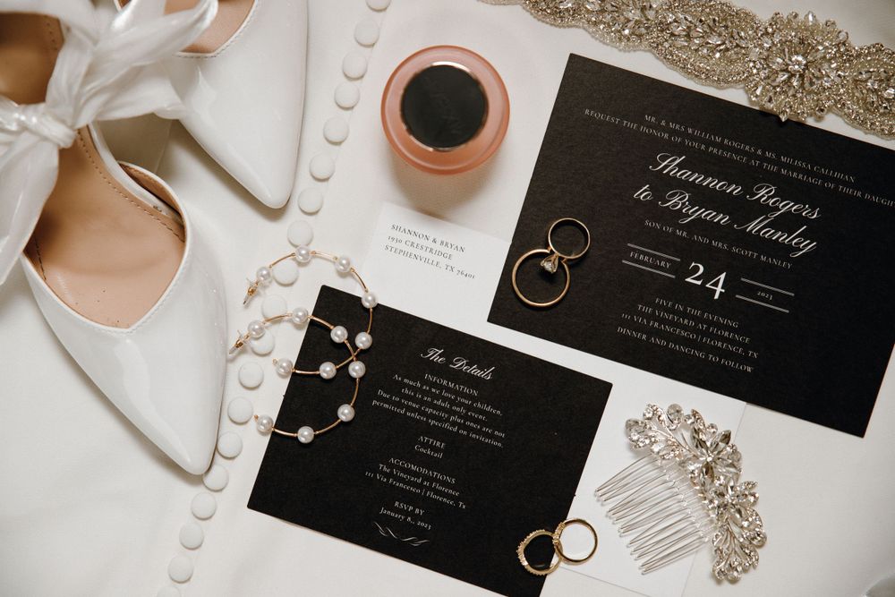 Wedding day flat lay featuring elegant shoes, invitations, perfume, jewelry, wedding rings, and accessories, all beautifully arranged.