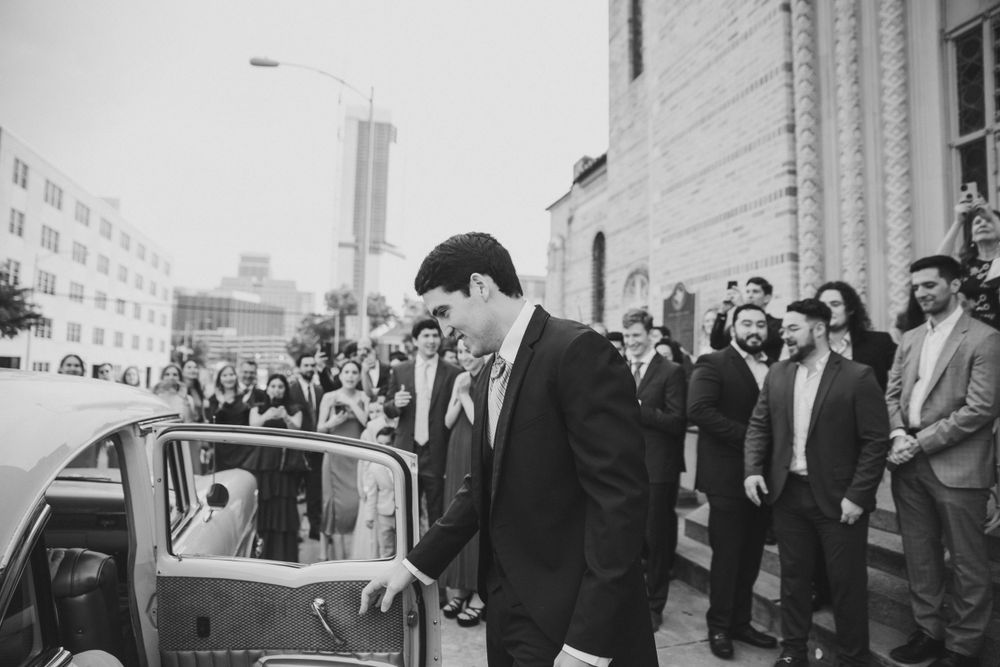 Groom opening the car door of his getaway car after the wedding ceremony, capturing a tender moment as he leads his bride away.