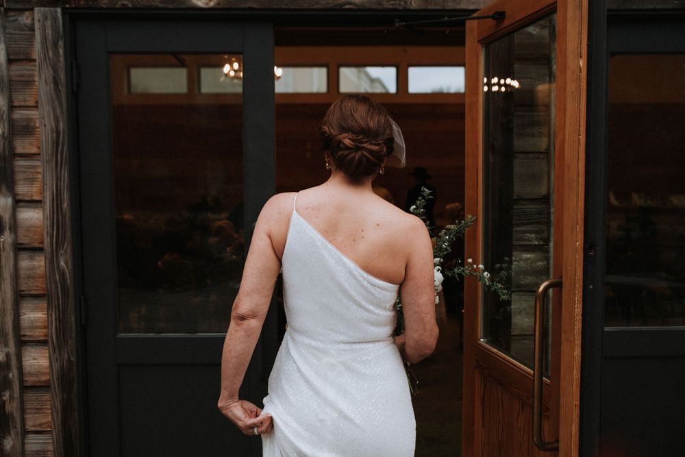 Bride walking into a room with a door held open by a loved one, capturing the anticipation and beauty of her wedding day entrance.