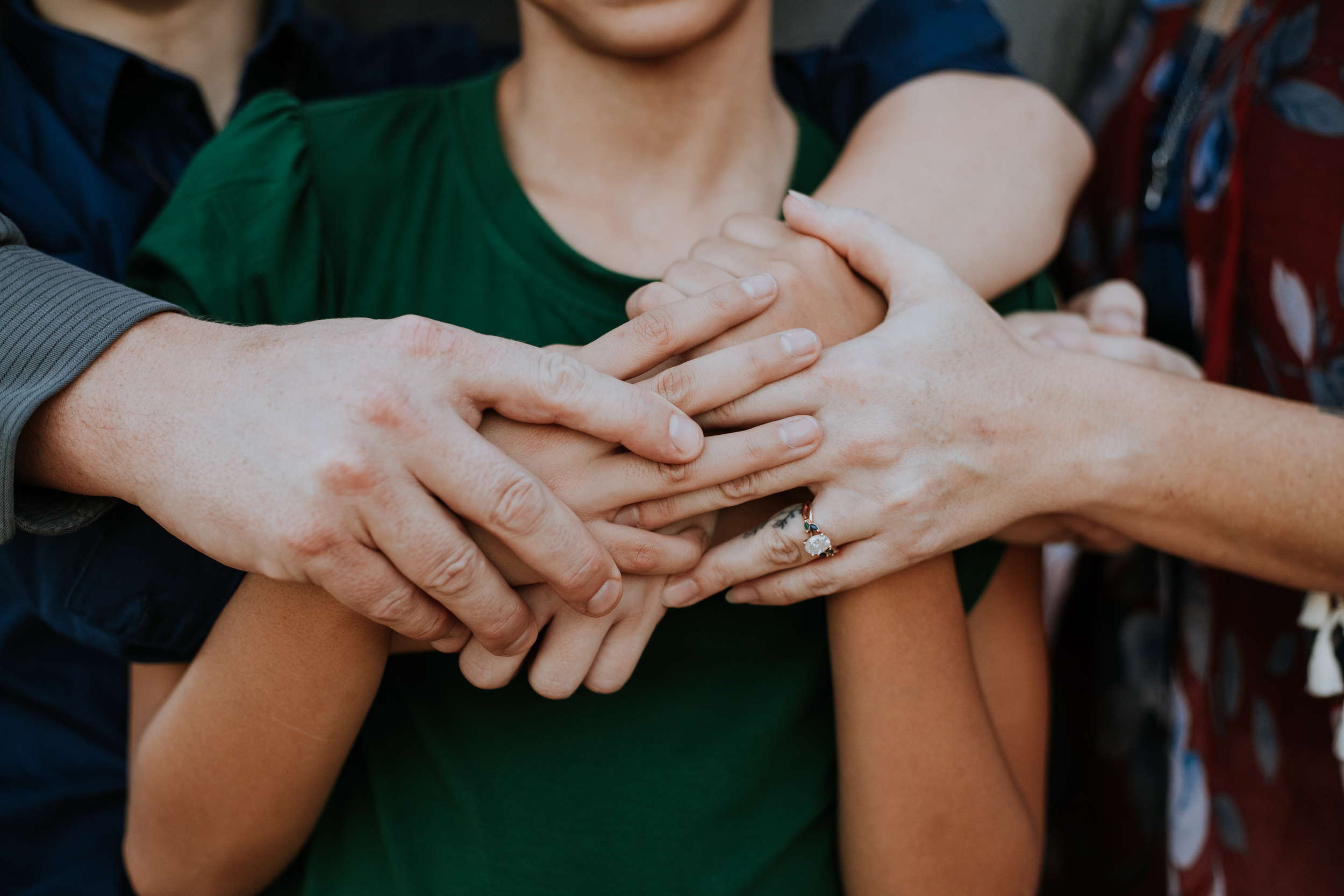 Closeup of family hands gently placed on the youngest member, symbolizing love, protection, and unity within the family.
