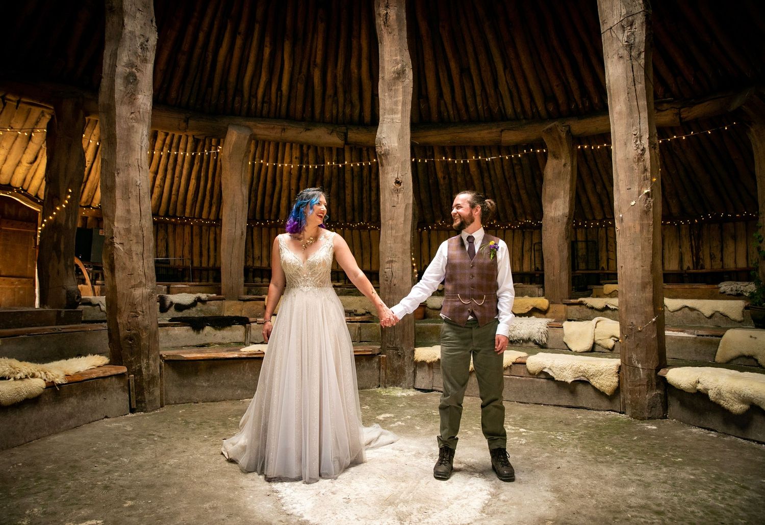 Couple dancing in a rustic wooden barn with string lights overhead.